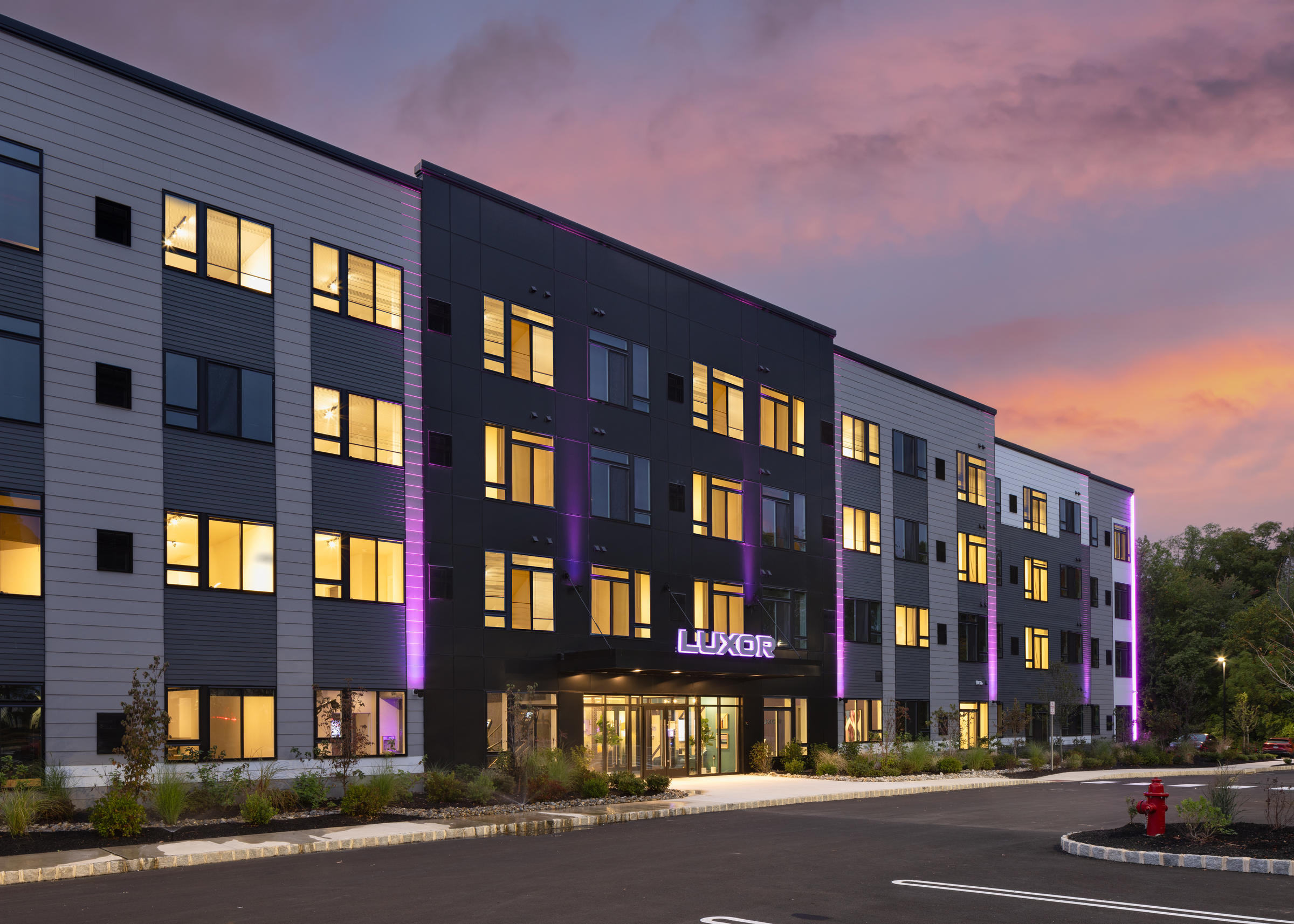 Westrum Corporate A modern apartment building with exterior lights at sunset, featuring the sign "Luxor" above the entrance.