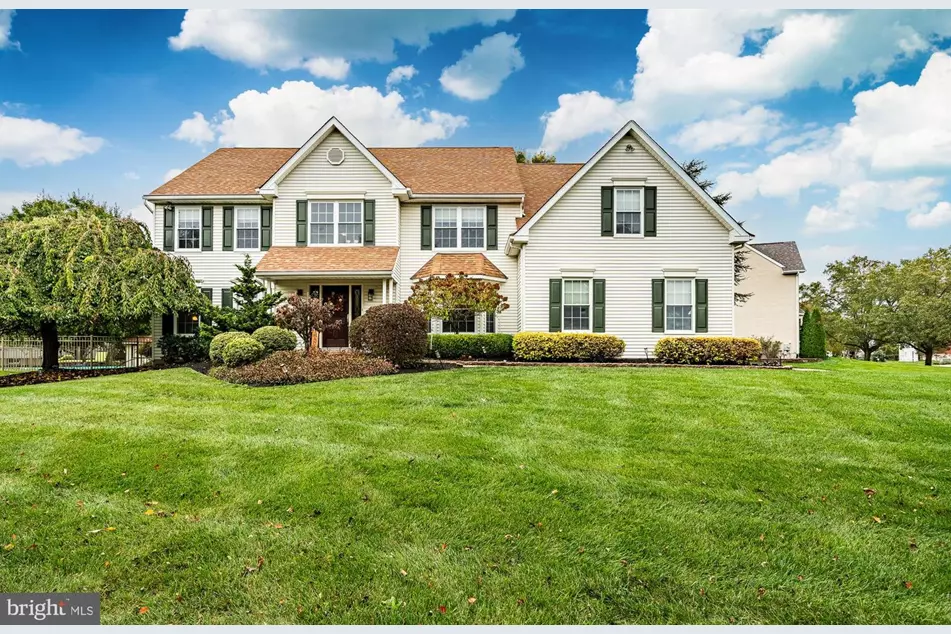 Westrum Corporate Spacious two-story white home with tan roof and lush lawn, nestled in scenic Lower Salford Township under a bright blue sky.