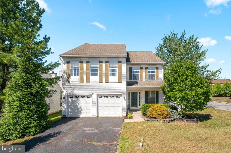 Westrum Corporate Two-story Perkiomen Township suburban house with double garage and tall windows; trees line the driveway on a sunny day.