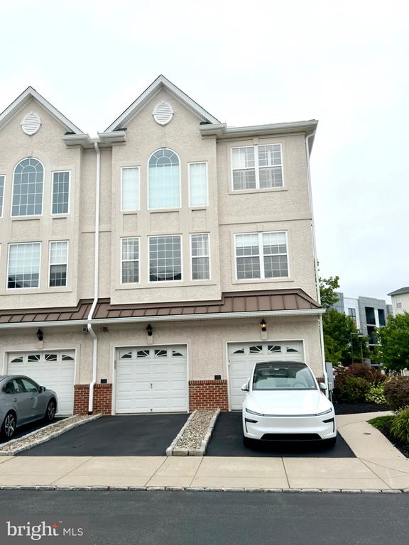 Westrum Corporate A white townhouse with three stories, arched windows, and a white car—classic Philadelphia luxury home in Villas at Packer Park.