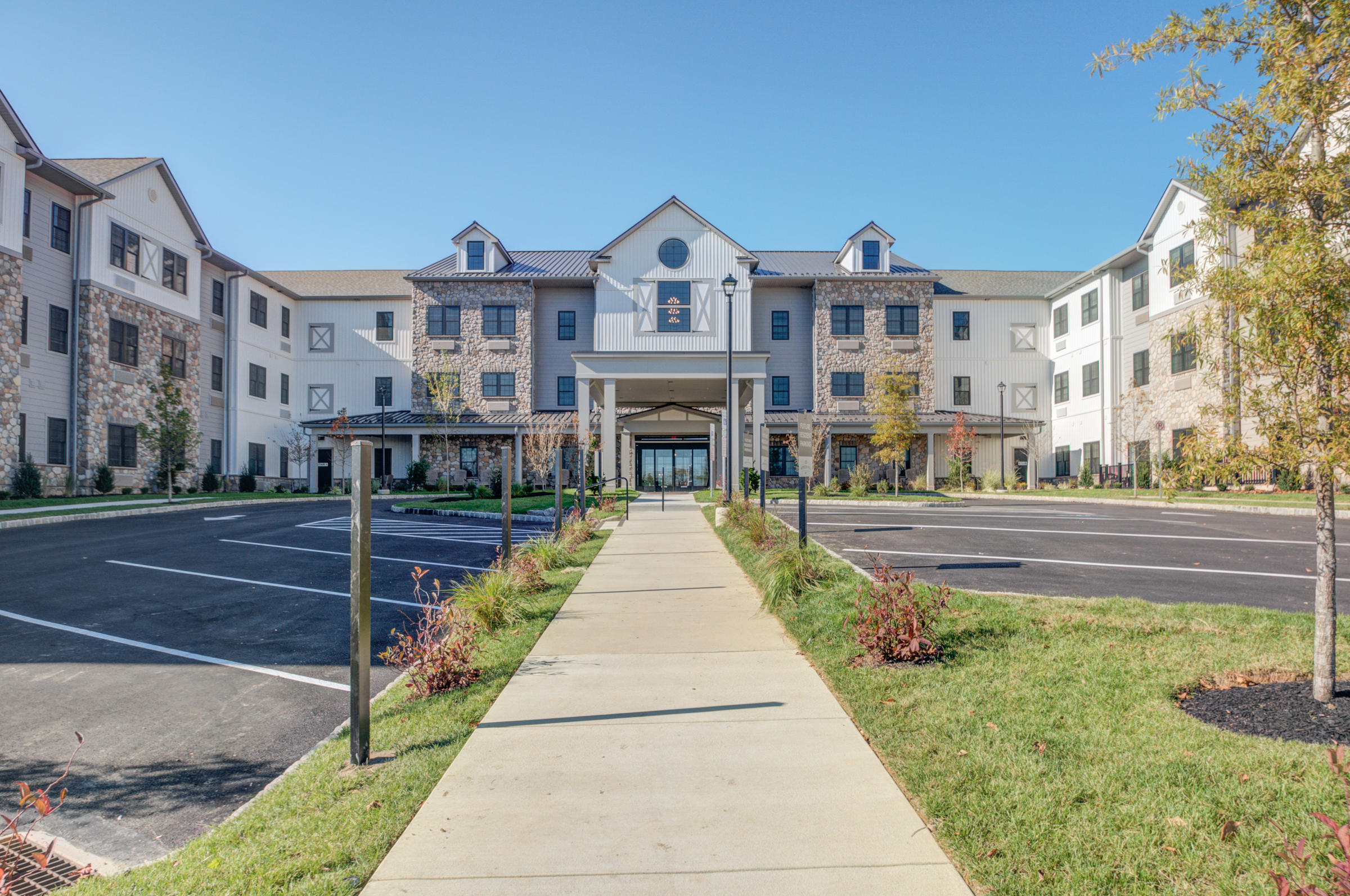 Westrum Corporate Wide sidewalk leads to a modern, three-story building with parking lots on both sides under a clear blue sky.
