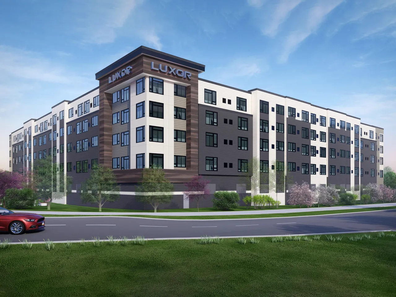 Westrum Corporate Modern five-story Luxor apartment in Fort Washington, featuring large windows, greenery, and a red car driving by out front.