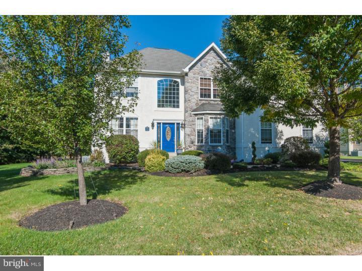 Westrum Corporate This Cambridge Knoll two-story home features a stone and white exterior, blue front door, large windows, and landscaped yard with trees.