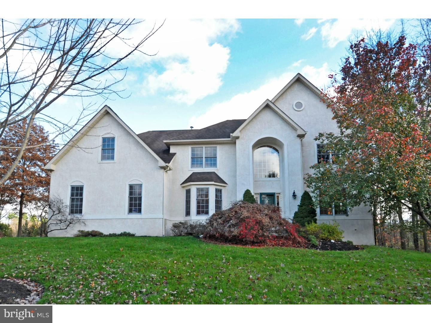 Westrum Corporate Two-story white house in Estates of Whitemarsh Hills with large windows, steep roof, and manicured lawn framed by autumn trees.