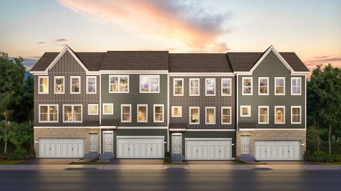 Westrum Corporate Modern three-story Neshaminy Springs townhouses with garages at sunset, featuring gray siding, stone accents, and large windows.