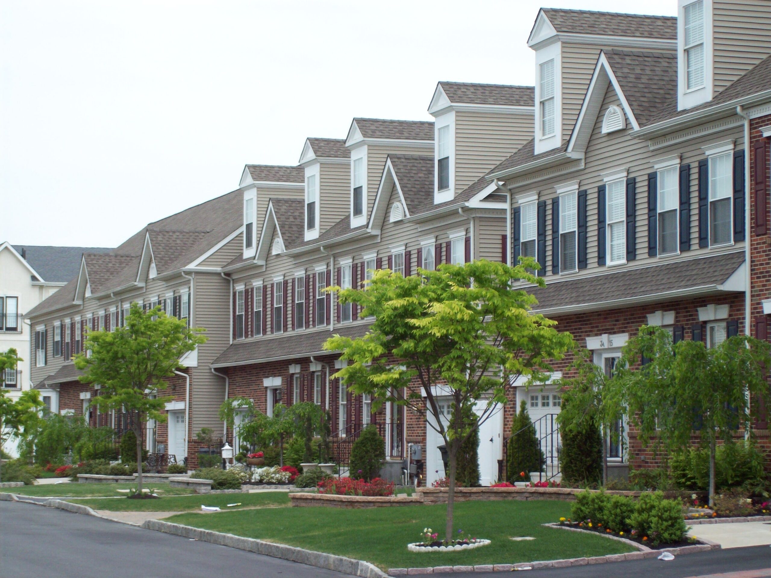 Westrum Corporate Row of modern townhouses in Reserve at Packer Park, with brick fronts and manicured lawns, lines a quiet Philadelphia street.