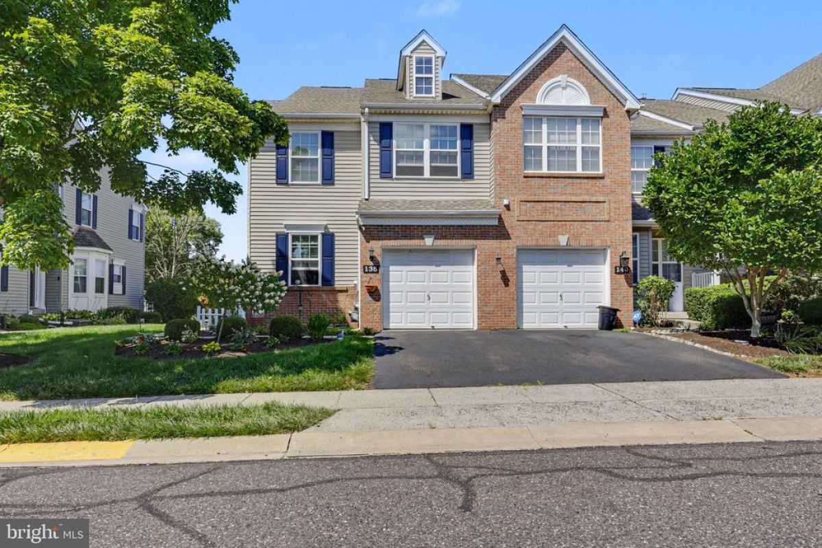 Westrum Corporate Two-story suburban house in Limerick Township with brick and siding, double garage, lawn, trees, and clear sky.