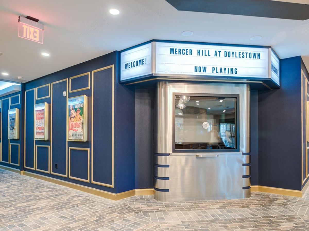 Westrum Corporate Movie theater lobby with vintage ticket booth, Doylestown posters, and marquee sign: “Mercer Hill at Doylestown Now Playing.”.