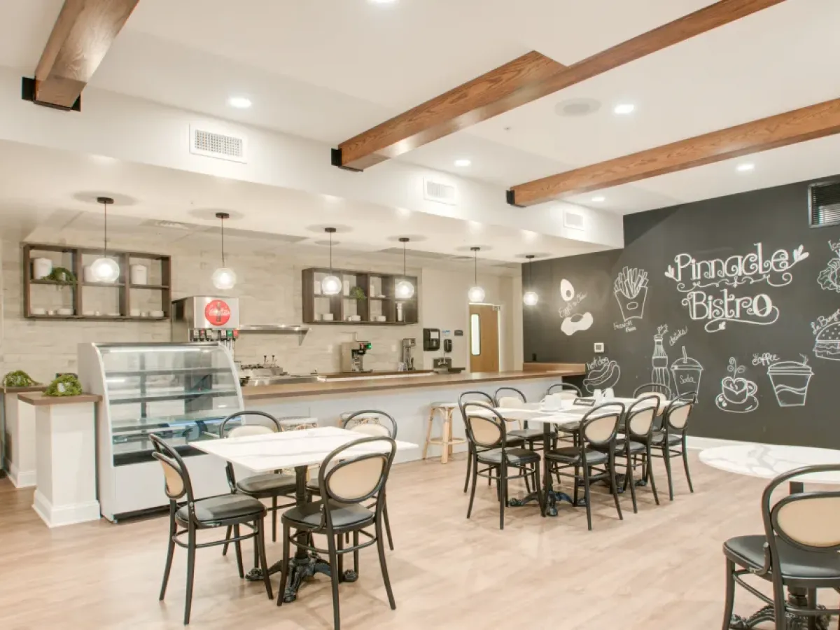 Westrum Corporate Modern cafe near Plymouth Meeting with round tables, black chairs, a display case, and a “Pinnacle Bistro” chalkboard wall.