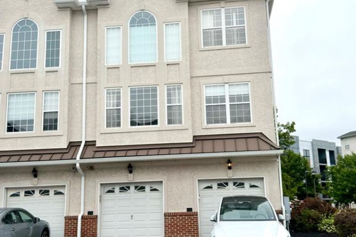 Westrum Corporate A white townhouse with three stories, arched windows, and a white car—classic Philadelphia luxury home in Villas at Packer Park.
