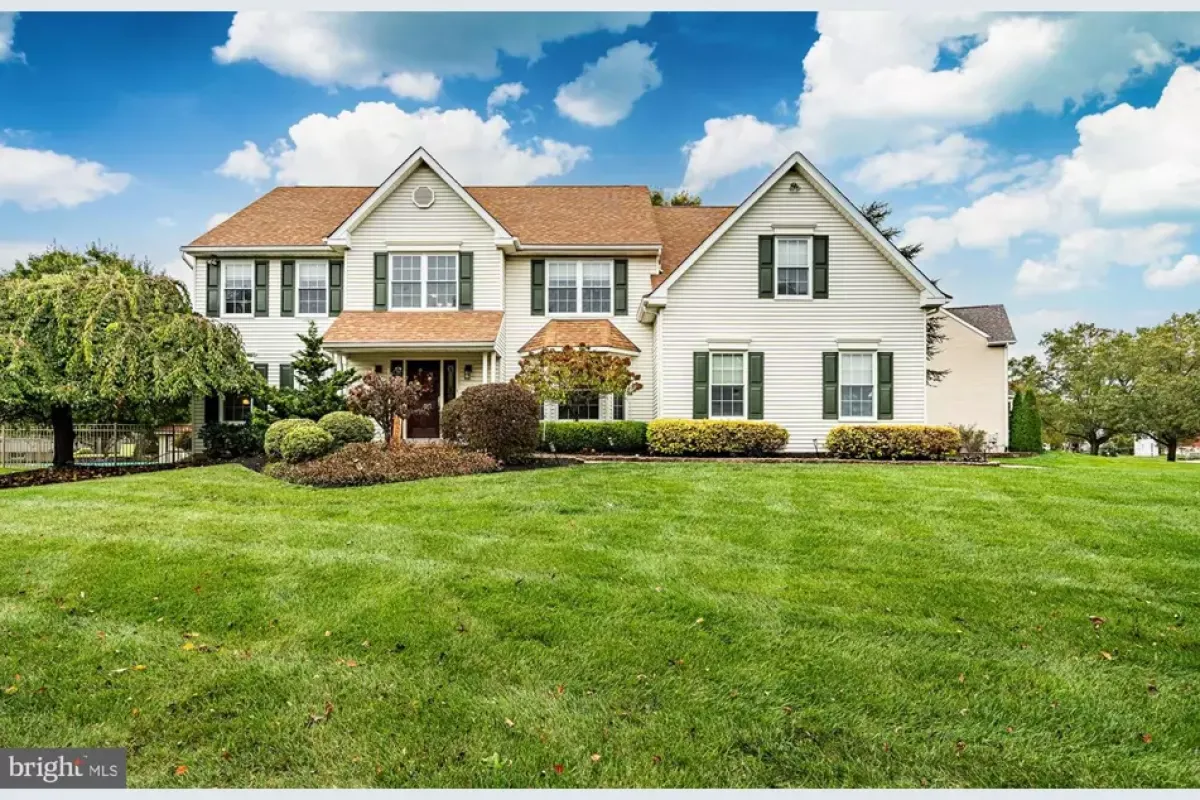 Westrum Corporate Spacious two-story white home with tan roof and lush lawn, nestled in scenic Lower Salford Township under a bright blue sky.