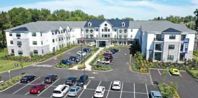 Westrum Corporate Aerial view of a modern three-story building with parked cars, surrounded by landscaped greenery and trees.