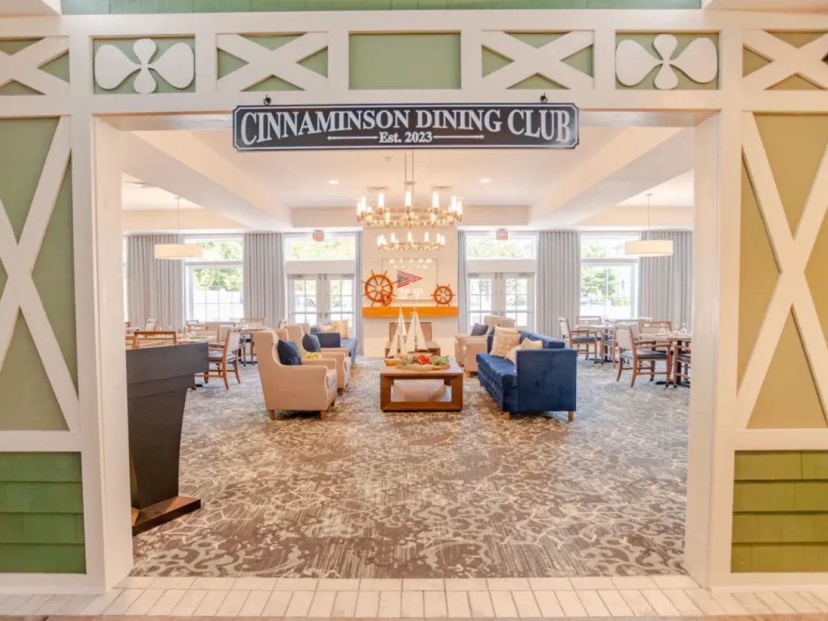 Westrum Corporate Bright dining room with blue couches, wooden tables, and a “Cinnaminson Dining Club” sign adds charm to the Azalea-inspired decor.