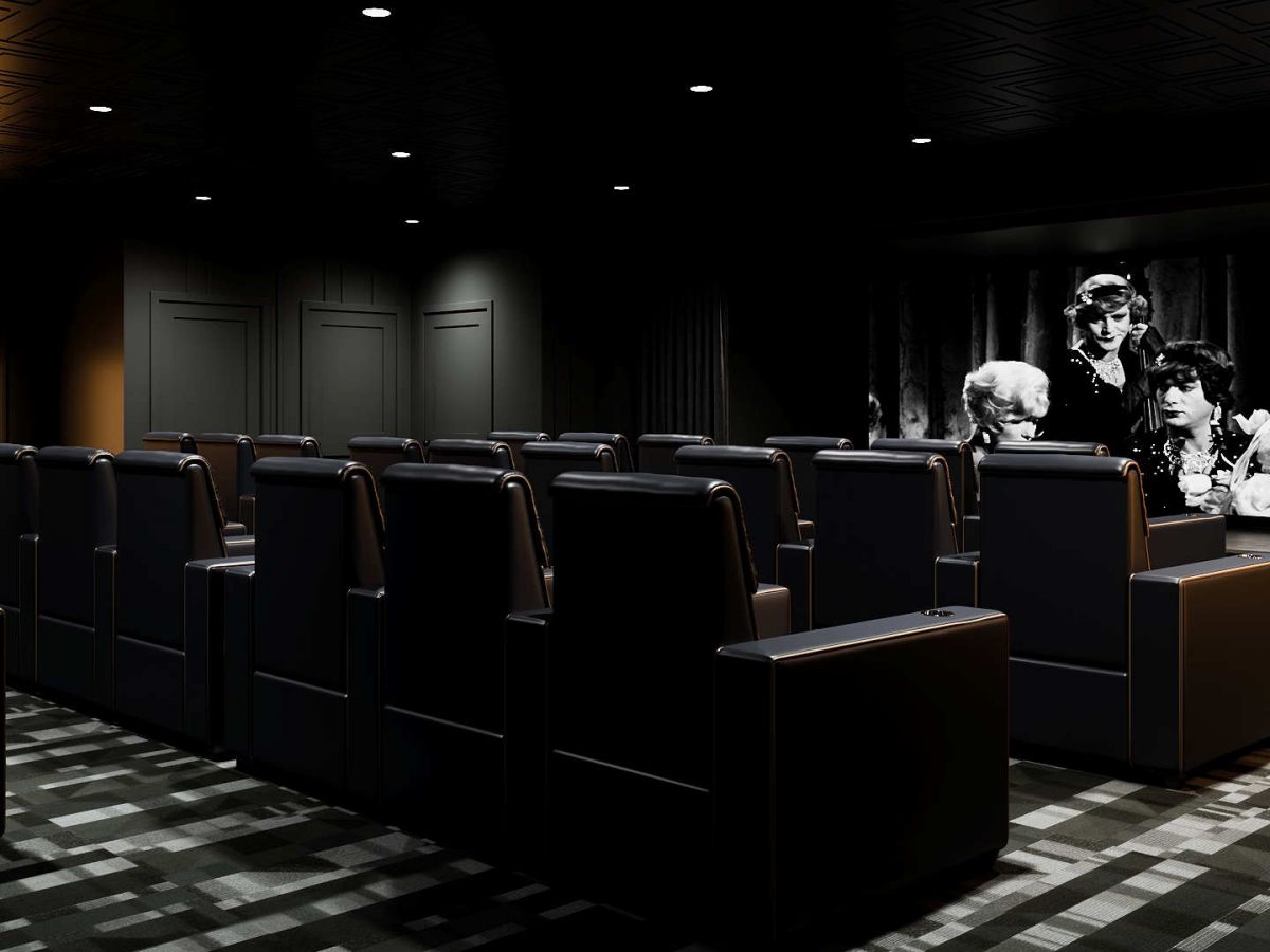 Westrum Corporate A small, modern theater at Aviv at Radnor with black seating and a black-and-white movie playing on the screen.