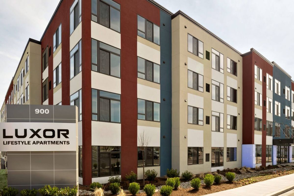 Westrum Corporate Modern apartment building with large windows and a sign that reads "LUXOR Lifestyle Apartments" at the entrance.