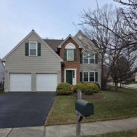 Westrum Corporate Two-story suburban house with green shutters, brick and siding exterior, double garage, and a mailbox in front yard.