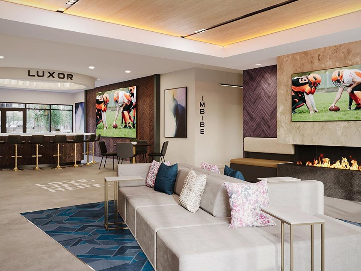 Westrum Corporate Modern lounge in Fort Washington with sofas, a fireplace, bar, TV airing football, and Luxor-inspired large windows for natural light.
