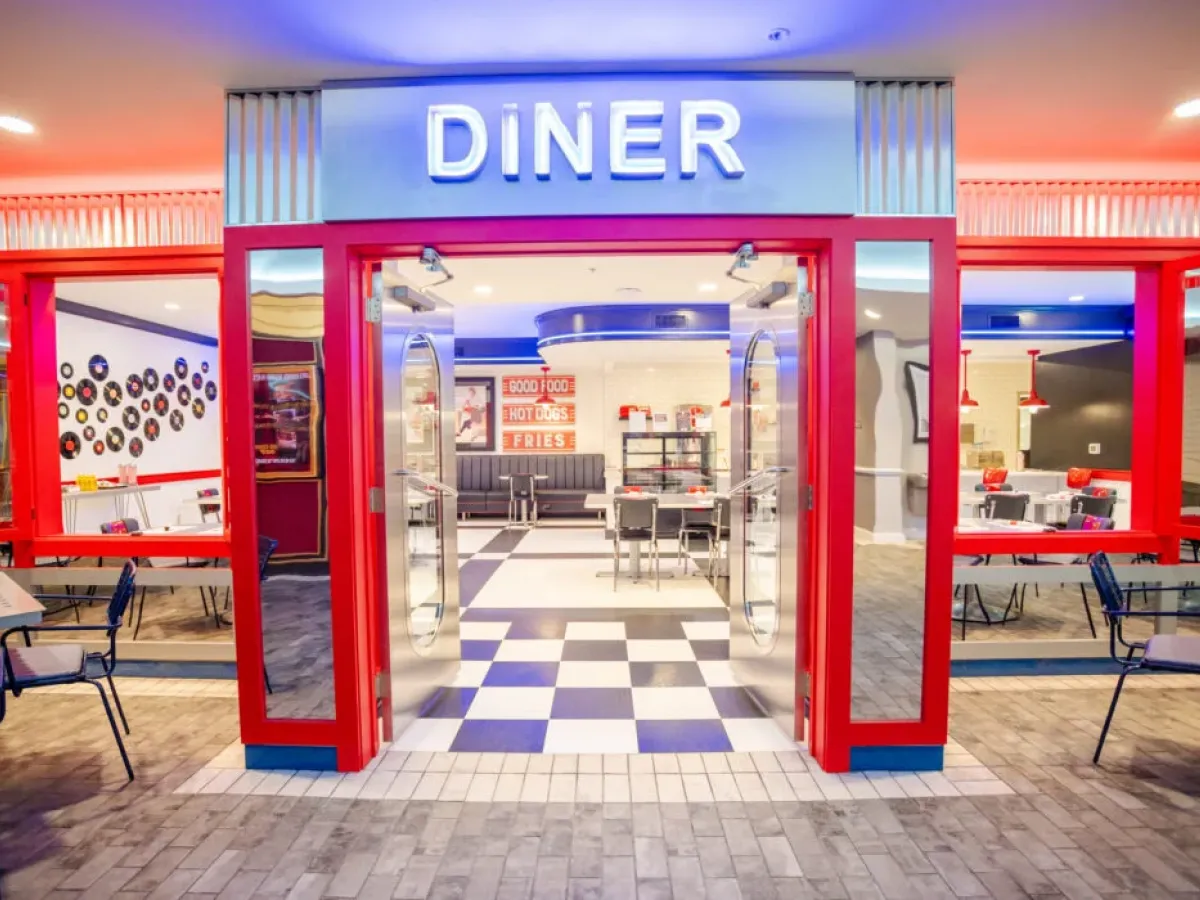 Westrum Corporate Retro-style diner entrance in Cinnaminson with red doors, neon “DINER” sign, checkered floor, and classic Azalea-inspired decor inside.