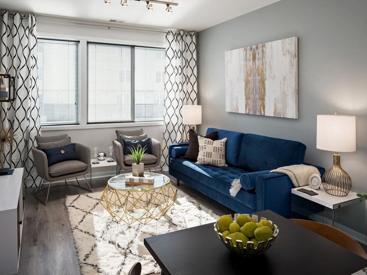 Westrum Corporate Modern living room at Pointe at 31, featuring a blue sofa, gold coffee table, and abstract art—luxury apartments in Brewerytown.