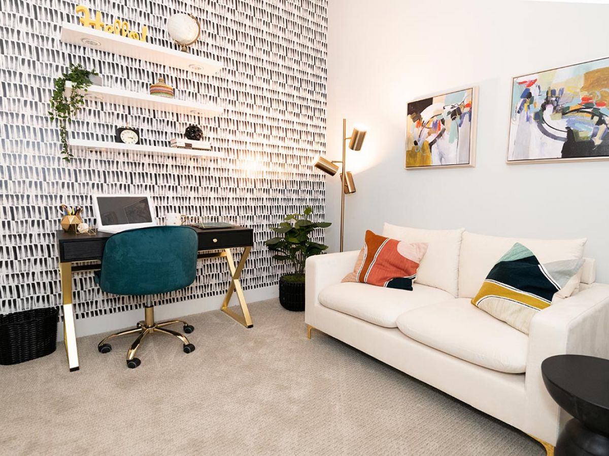 Westrum Corporate Modern home office at Luxor Bala Cynwyd with a desk, green chair, shelves, abstract art, and geometric pillows on beige carpet.