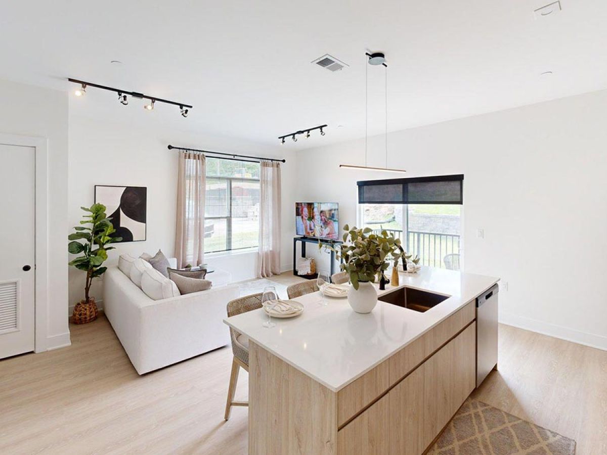 Westrum Corporate Modern open living room and kitchen at Foundry Flats with white walls, light wood floors, and large windows letting in natural light.