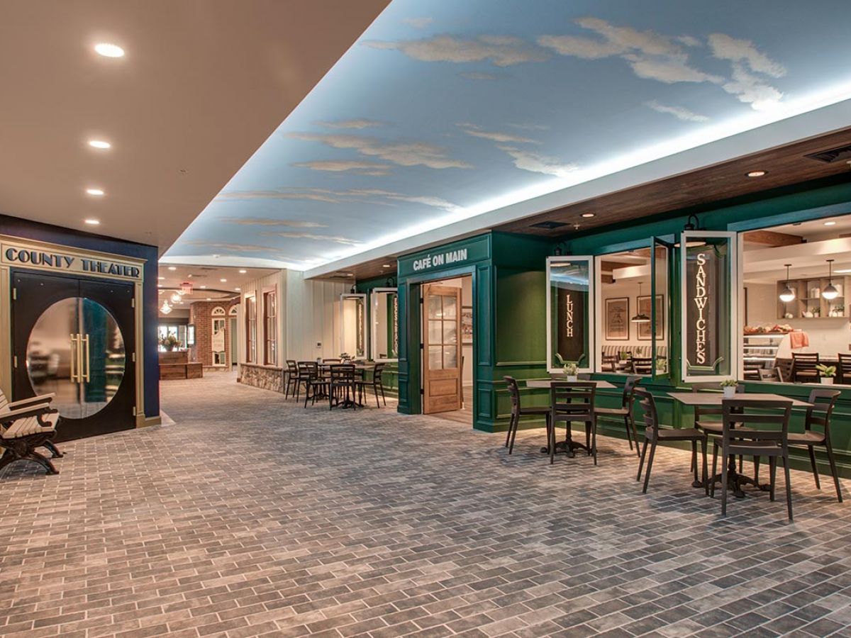 Westrum Corporate Mercer Hill at Doylestown offers senior living with café tables, restaurant fronts, and a theater under a sky-painted ceiling.
