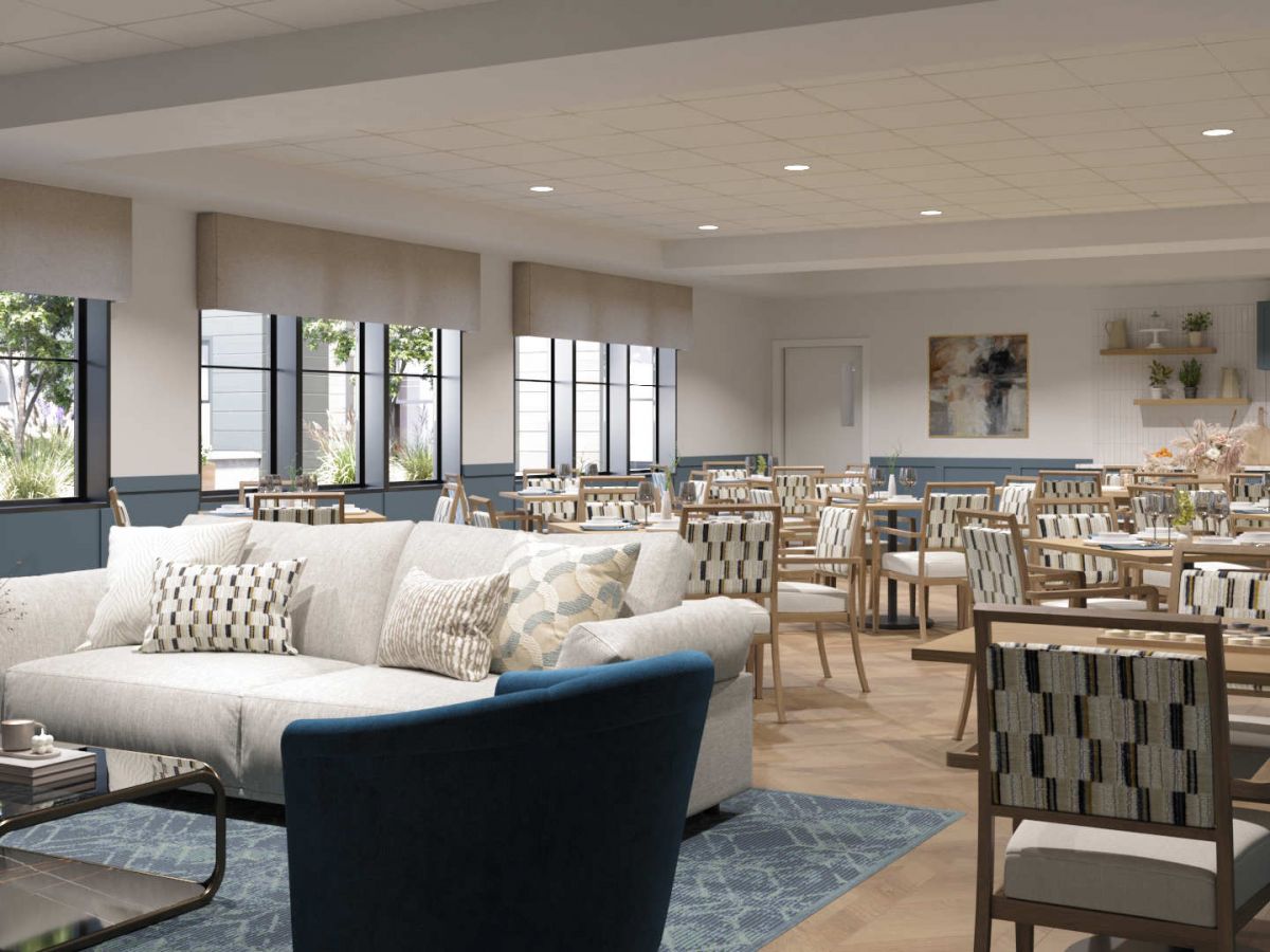 Westrum Corporate A spacious, modern dining area at Aviv at Radnor features wooden tables, cushioned chairs, and a white sofa near large windows.
