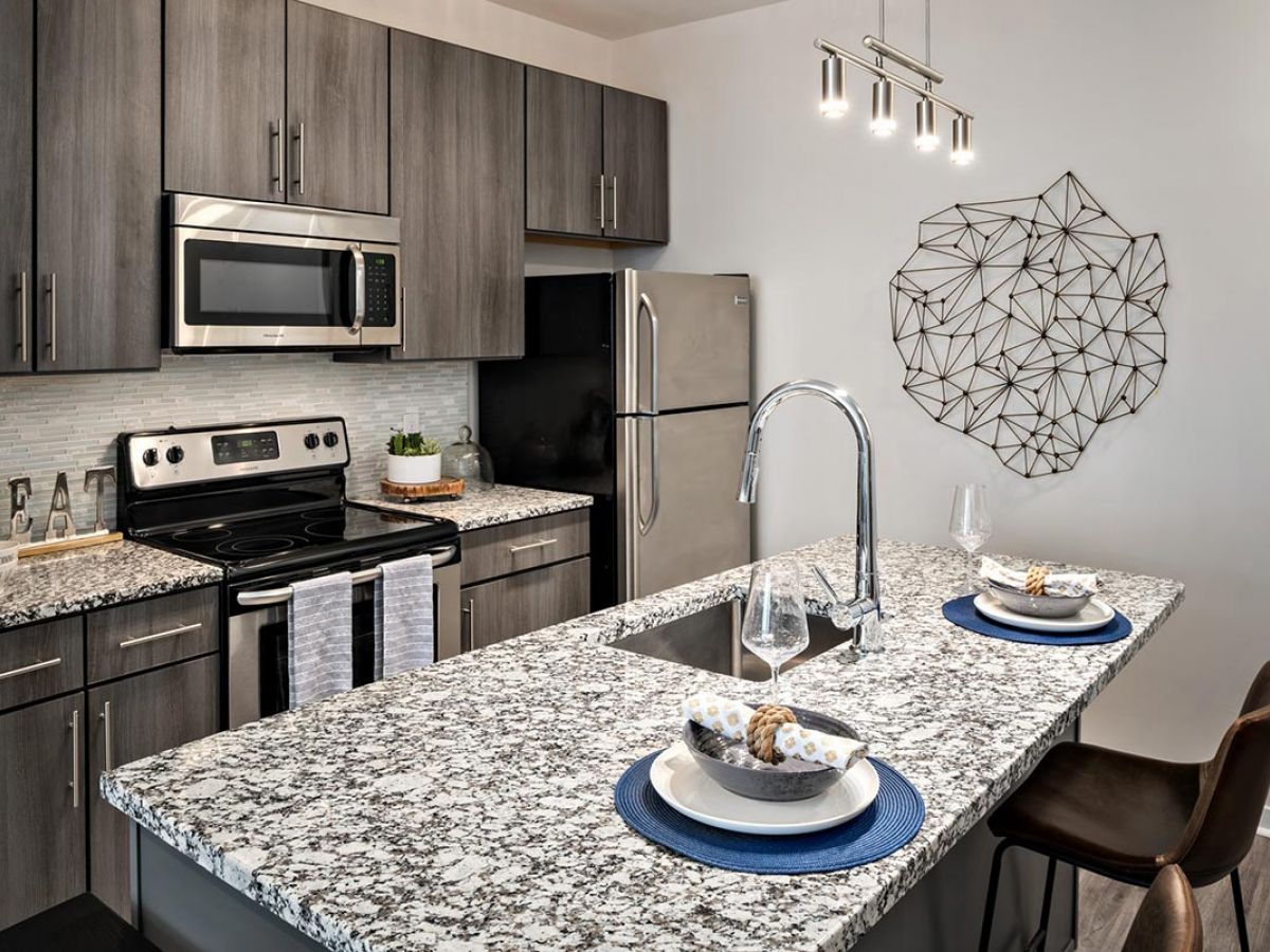 Westrum Corporate Modern kitchen at The Pointe at 31 Brewerytown with granite countertops, stainless steel appliances, and blue-matted island seating.