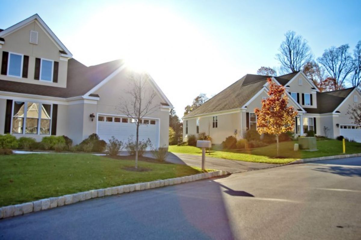Westrum Corporate Suburban street in Whitemarsh Township with modern houses, green lawns, shady trees, and a bright sun in the background.
