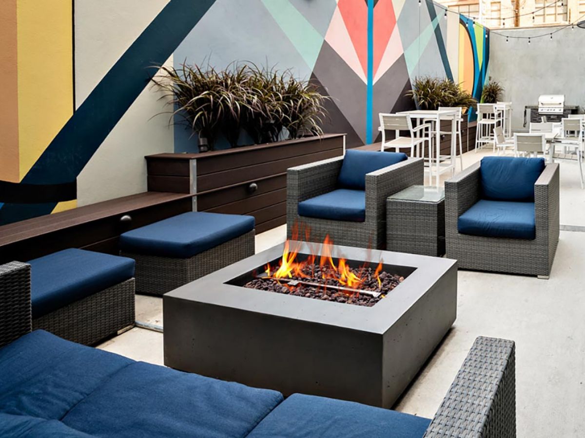Westrum Corporate Modern outdoor patio at 1200 Washington apartments, featuring wicker chairs, a fire pit, and a vibrant geometric mural.