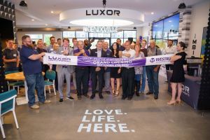 Westrum Corporate A group of people at an apartment grand opening, holding a purple ribbon that says “Grand Opening September 6th, 2022.”.