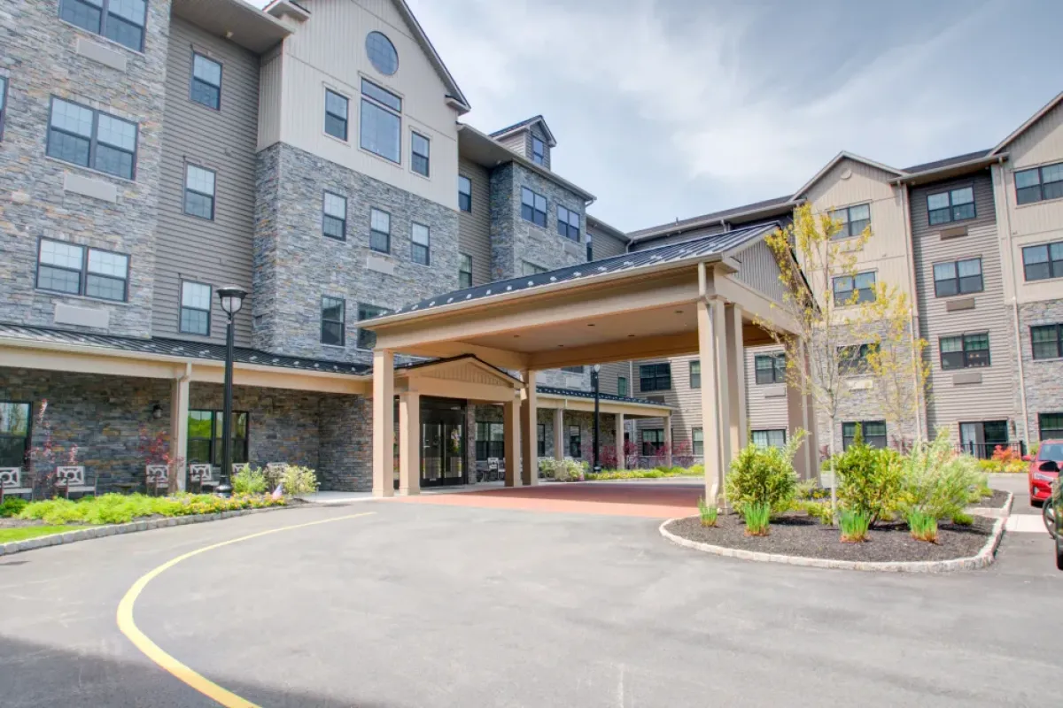 Westrum Corporate Pinnacle at Plymouth Meeting: a four-story building with stone and beige siding, covered entrance, driveway, and landscaped greenery.