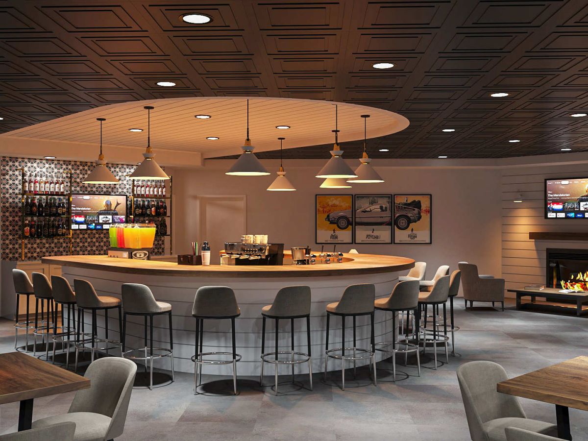 Westrum Corporate Aviv at Radnor features a circular counter, grey chairs, warm lighting, a cozy fireplace, TV screens, and wooden tables with small lamps.