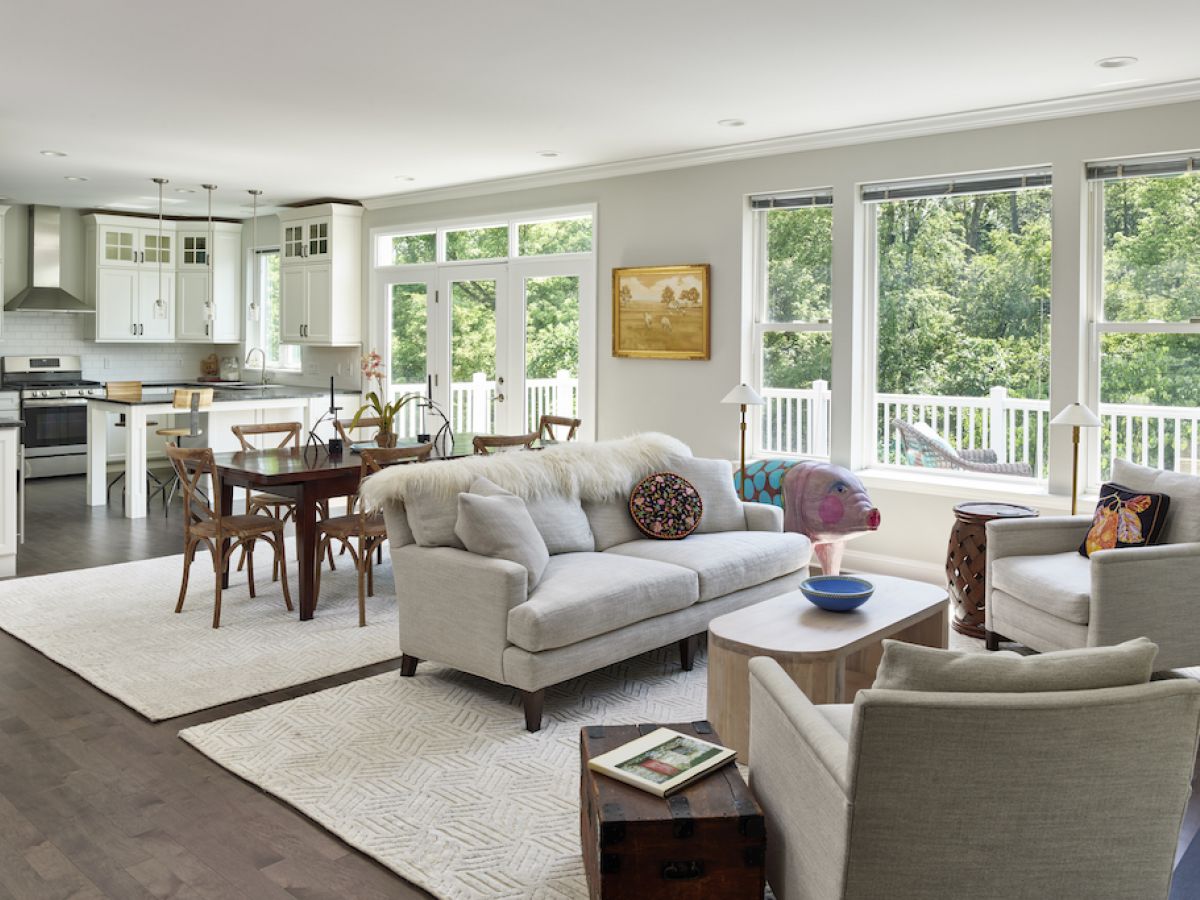 Westrum Corporate Bright, modern open-plan living and dining area in Whitemarsh Township with large windows and views of green trees outside.