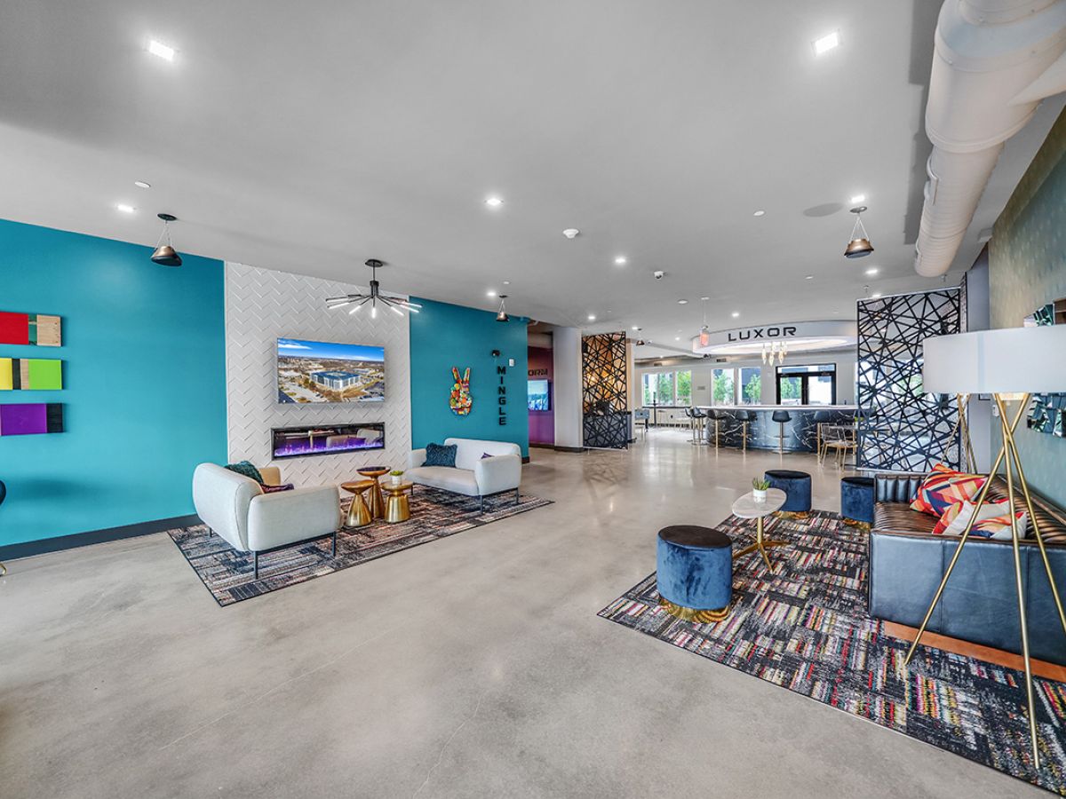 Westrum Corporate Modern lounge in West Chester with colorful decor, teal accent wall, Luxor couches, stylish rugs, wall art, and natural light.