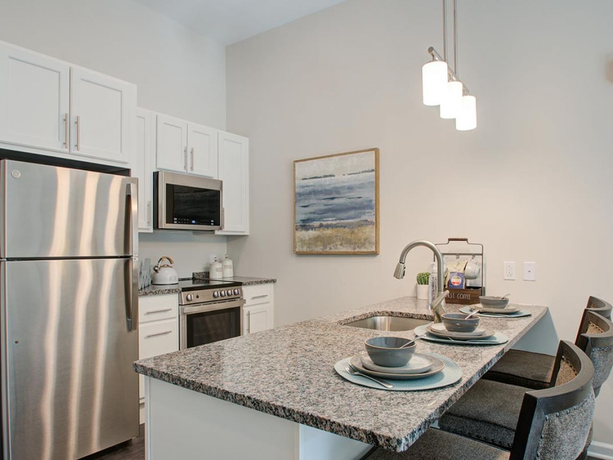 Westrum Corporate Modern Mercer Hill kitchen with stainless steel appliances, granite island, and abstract wall art in Doylestown senior living.