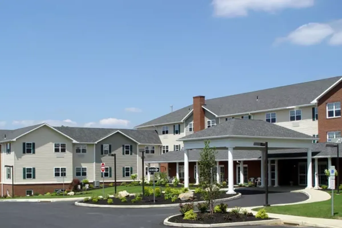 Westrum Corporate A large, modern senior living facility with a driveway, landscaped garden, and clear blue sky.