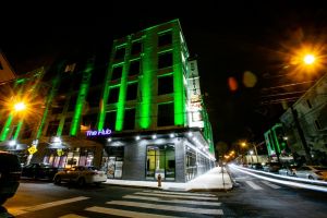 Westrum Corporate A modern building at night is lit with green lights, with cars parked along the street and light trails from passing cars.