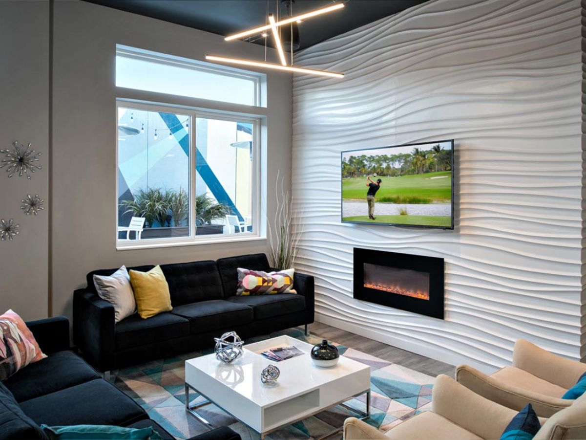 Westrum Corporate Modern living room at 1200 Washington features a wavy white accent wall, TV, fireplace, black sofa, armchairs, and geometric décor.