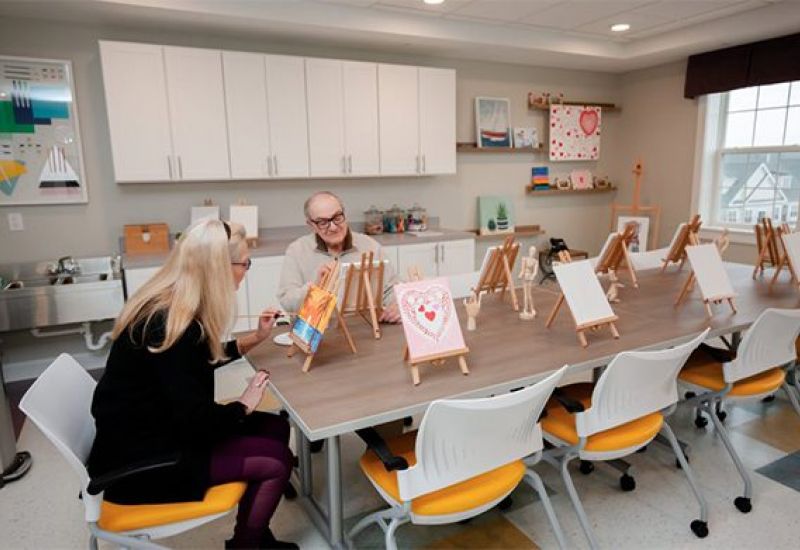 Westrum Corporate Two older adults paint at easels in a bright art room at Pointe@31 Brewerytown, reflecting community excellence and creativity.