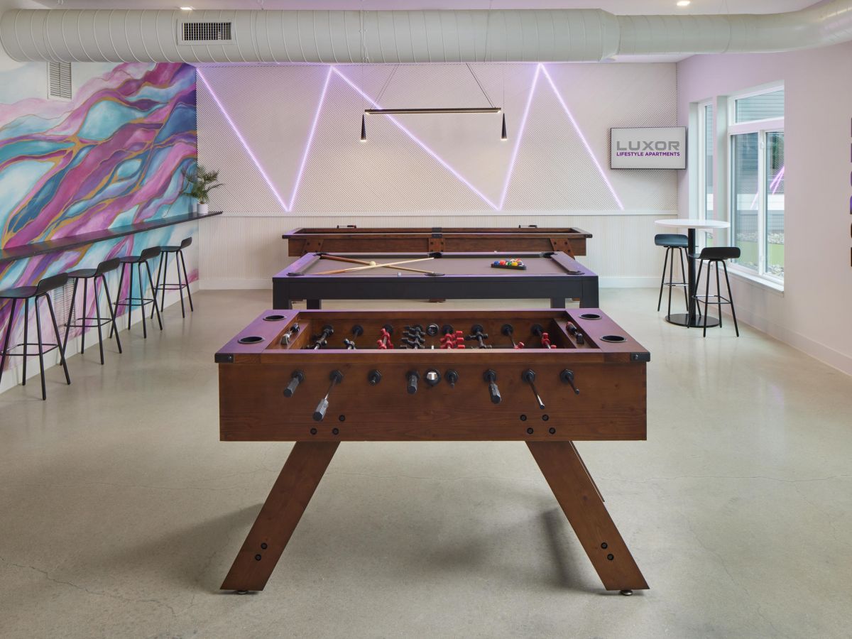 Westrum Corporate Game room at Luxor Montgomeryville in Montgomeryville PA with foosball, pool tables, mural wall, neon lights, and an "ENGAGE" sign.