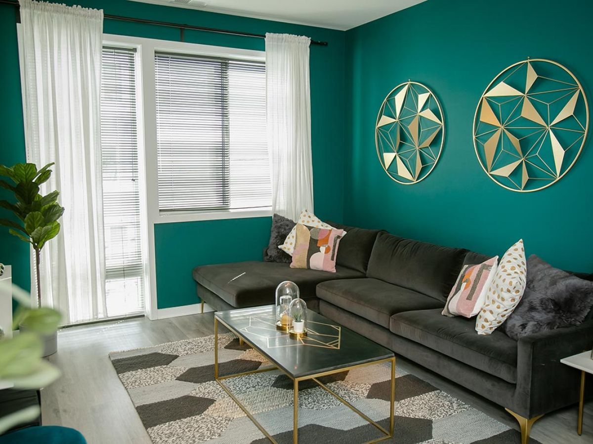 Westrum Corporate Teal living room in The Hub at 31 Brewerytown with a gray sectional, glass coffee table, and bright windows—modern Philadelphia apartments style.
