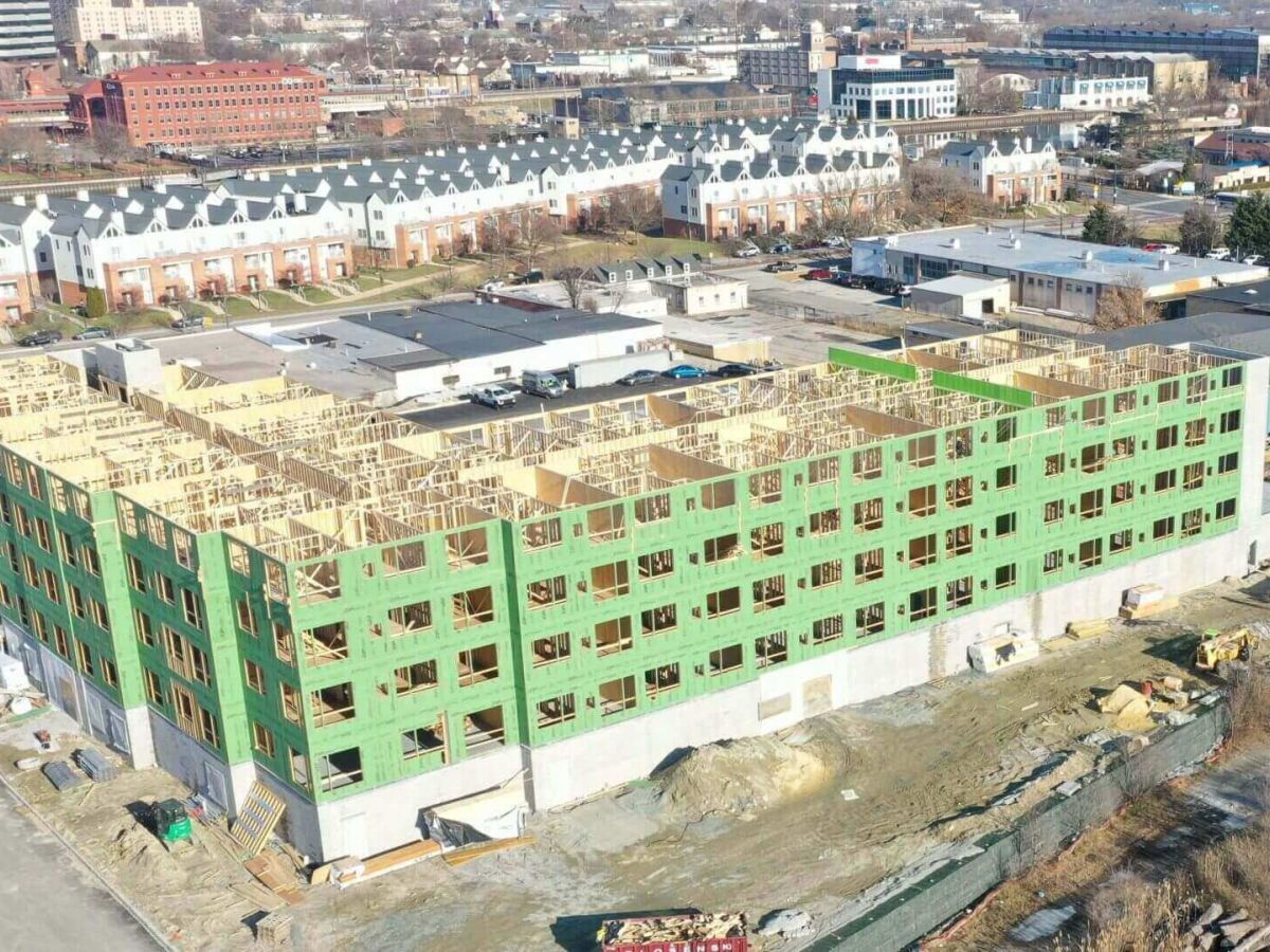 Westrum Corporate Aerial view of a large, partially constructed apartment building with green sheathing and exposed wood framing.