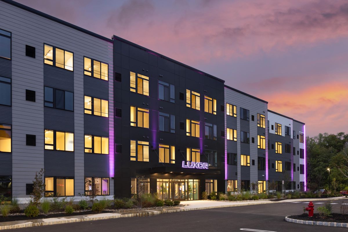 Westrum Corporate Modern Luxor Montgomeryville apartments with purple accent lights, sunset views, parking, and a landscaped entryway await you in Montgomeryville.