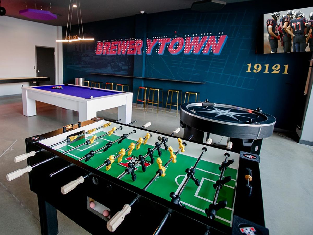 Westrum Corporate Modern game room at The Hub at 31, Brewerytown, with foosball, pool table, bar seating, and “Drewrytown” wall decor.