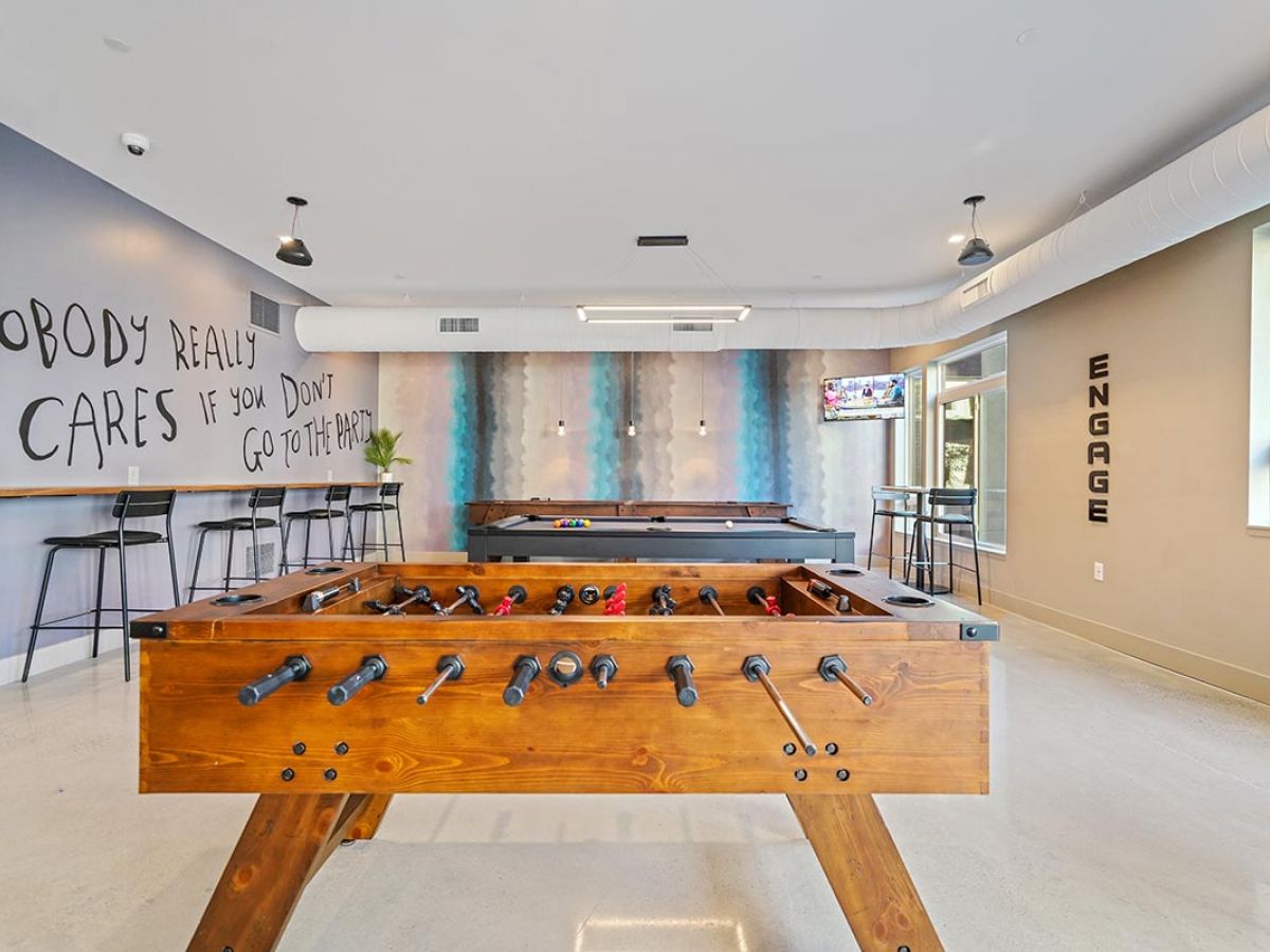 Westrum Corporate Modern game room at Luxor Lansdale with foosball, pool tables, high stools, wall art, TV, bright lighting, and minimalist decor.