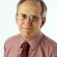 Westrum Corporate Older man wearing glasses, a red checkered shirt, and a red patterned tie, posing in front of a plain white background.