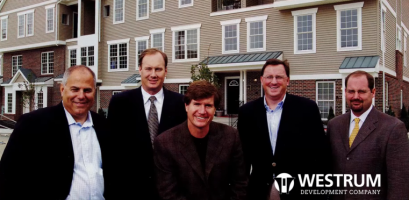 Westrum Corporate Five men in business attire stand in front of a building, smiling. "WESTRUM DEVELOPMENT COMPANY" logo is in the bottom right corner.