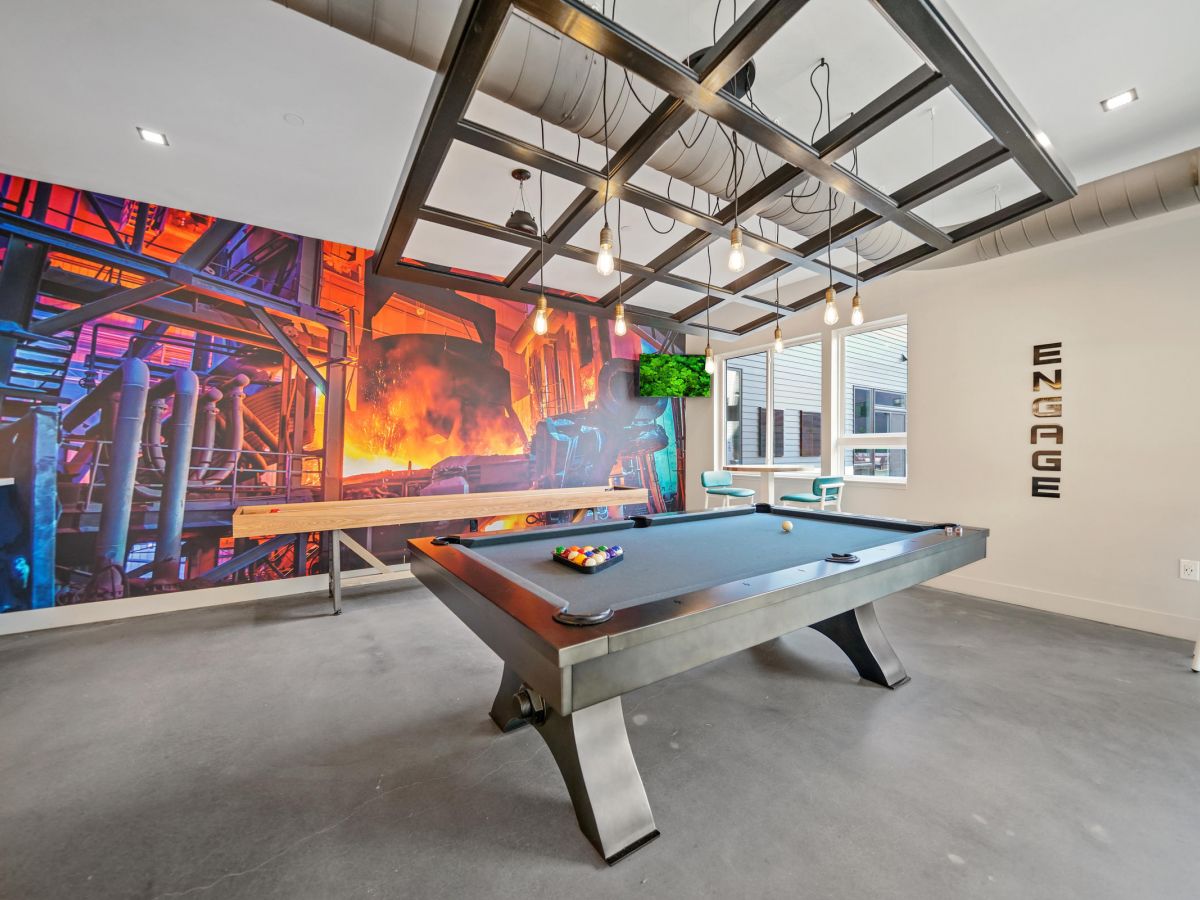 Westrum Corporate Modern game room with a pool table, colorful wall mural, TV, high chairs, and the word "ENGAGE" on the wall.