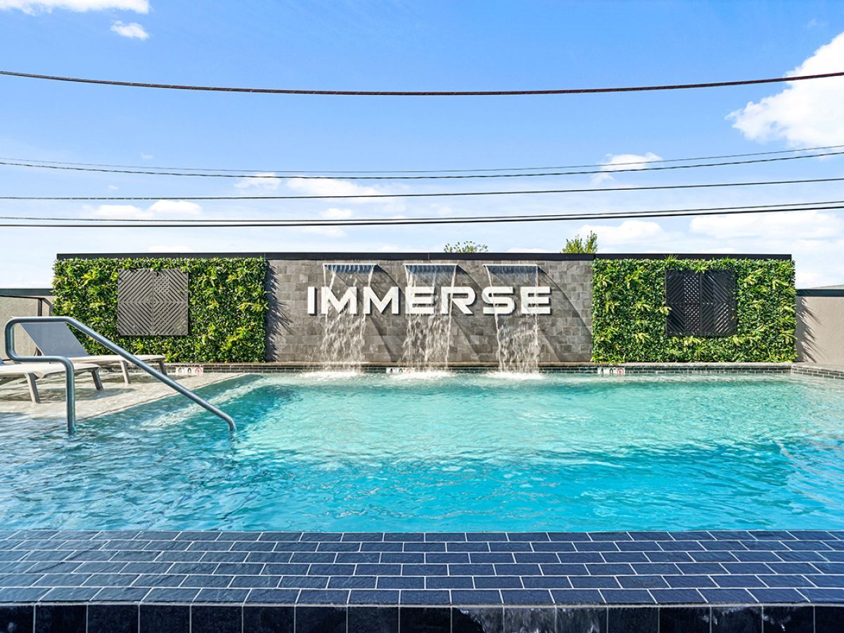 Westrum Corporate Luxor Phoenixville outdoor pool features water elements, lush green wall panels, and “IMMERSE” displayed centrally.
